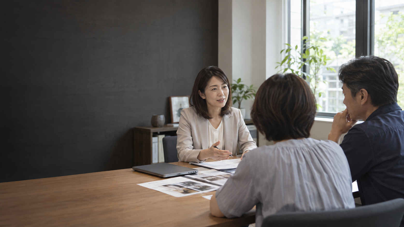 相談室で顧客夫婦の話を聞く日本人アドバイザー